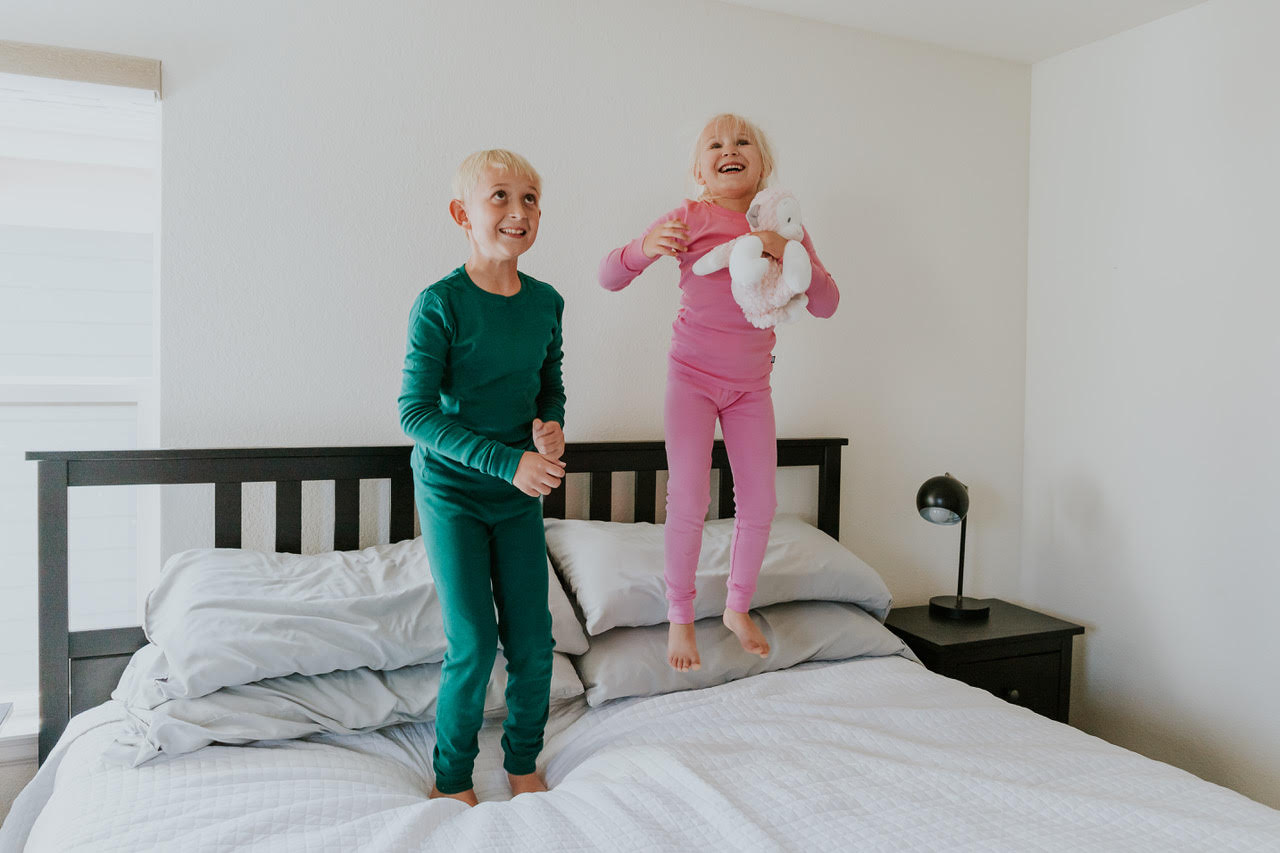 Kids in organic pajamas jumping on a bed together