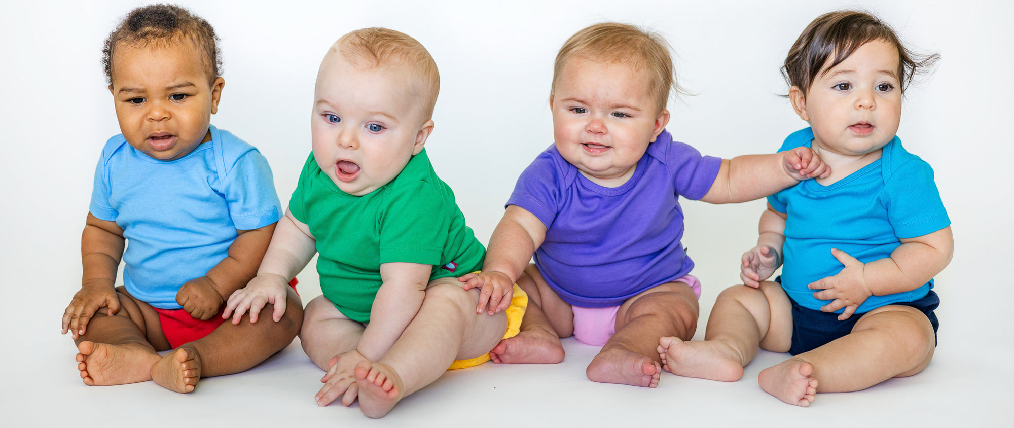 Four babies wearing organic cotton short sleeve onesies and diaper covers