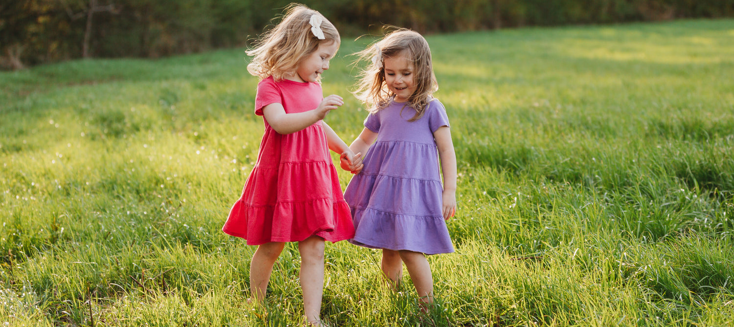 Girls in cute colorful cotton dresses in a field of grass